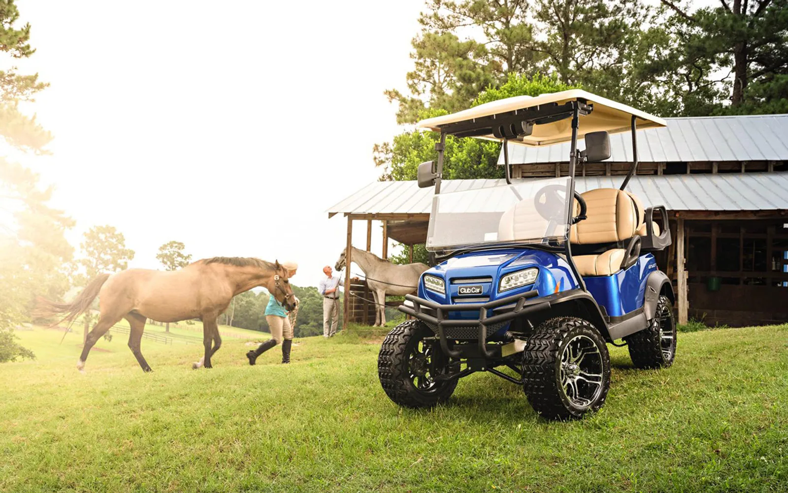 A Club Car Onward in Pearl Blue on a horse farm, a rider leading a horse behind it