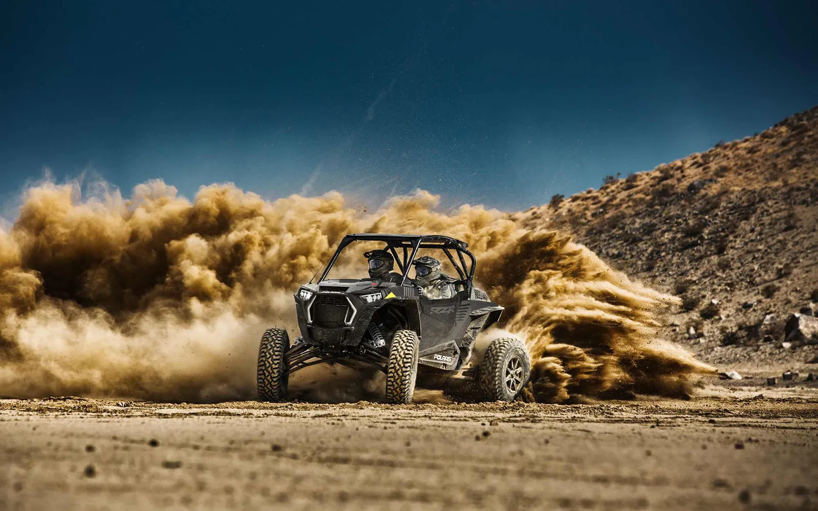 A Polaris RZR tearing through dust