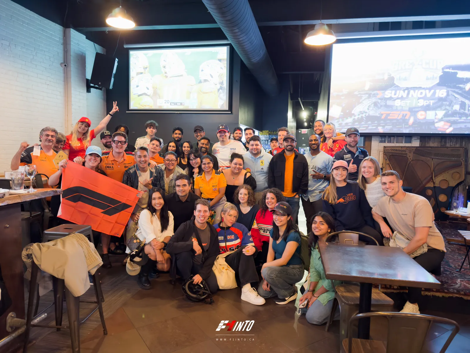 A full F1inTO race day room in for the group photo, flag out, the big screens behind them