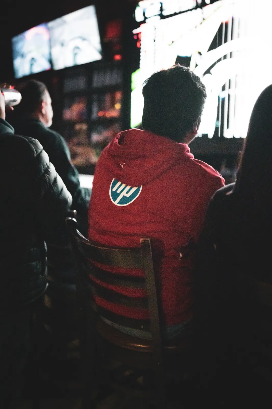 A fan in a red hoodie watching the wall of screens at an F1inTO race day