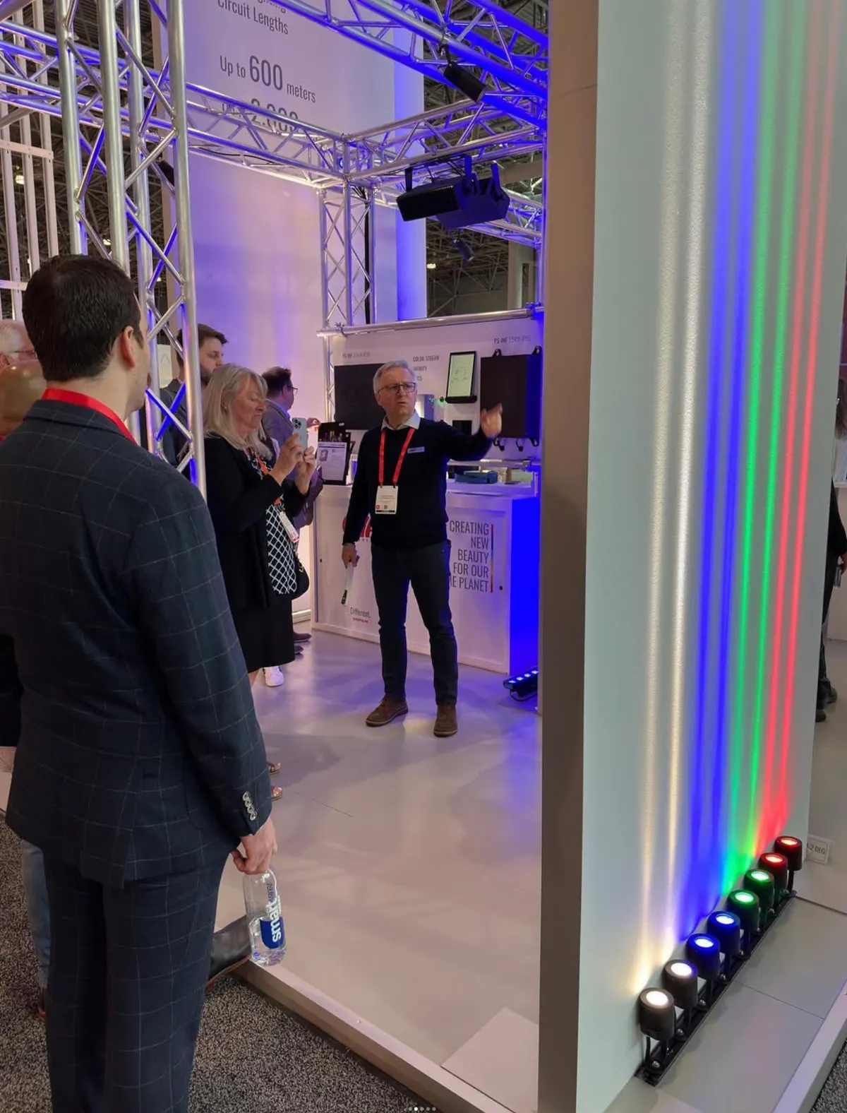 Visitors talking beside an RGB-lit column on the GVA Lighting stand