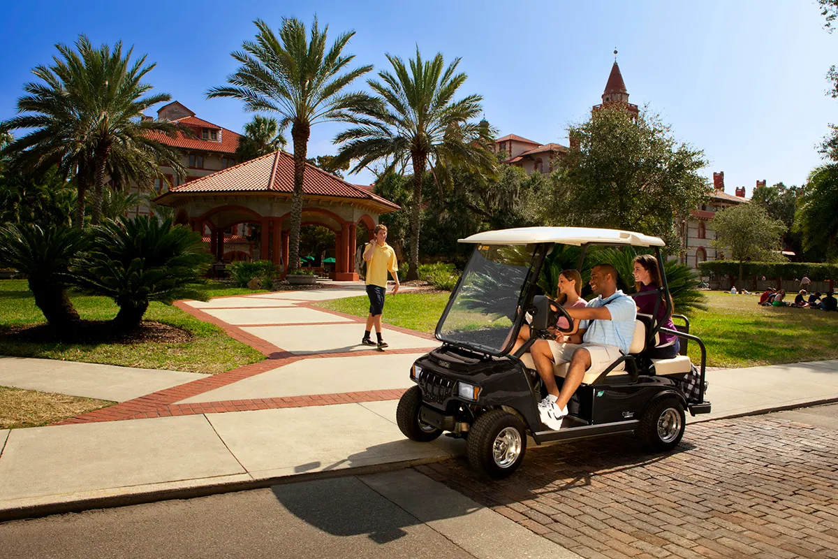 Club Car golf cart on a resort path among palm trees