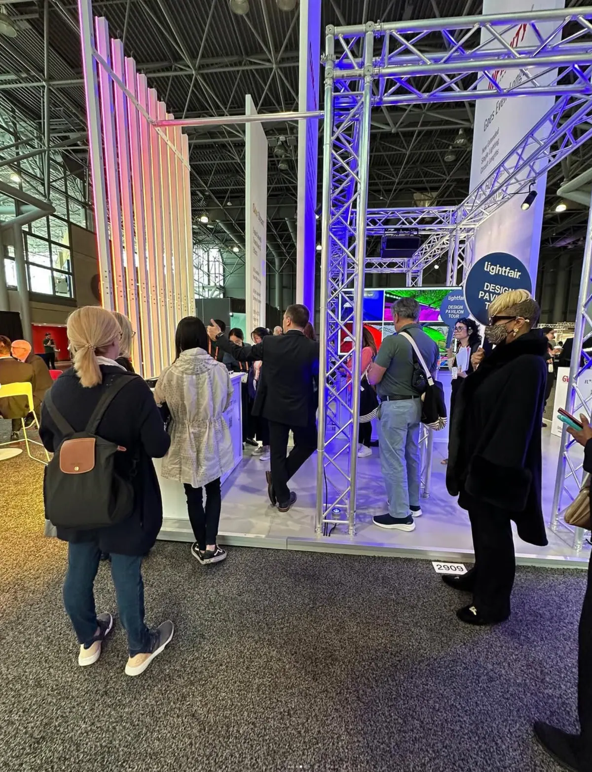 Show floor crowd moving around the GVA Lighting stand and its truss structure
