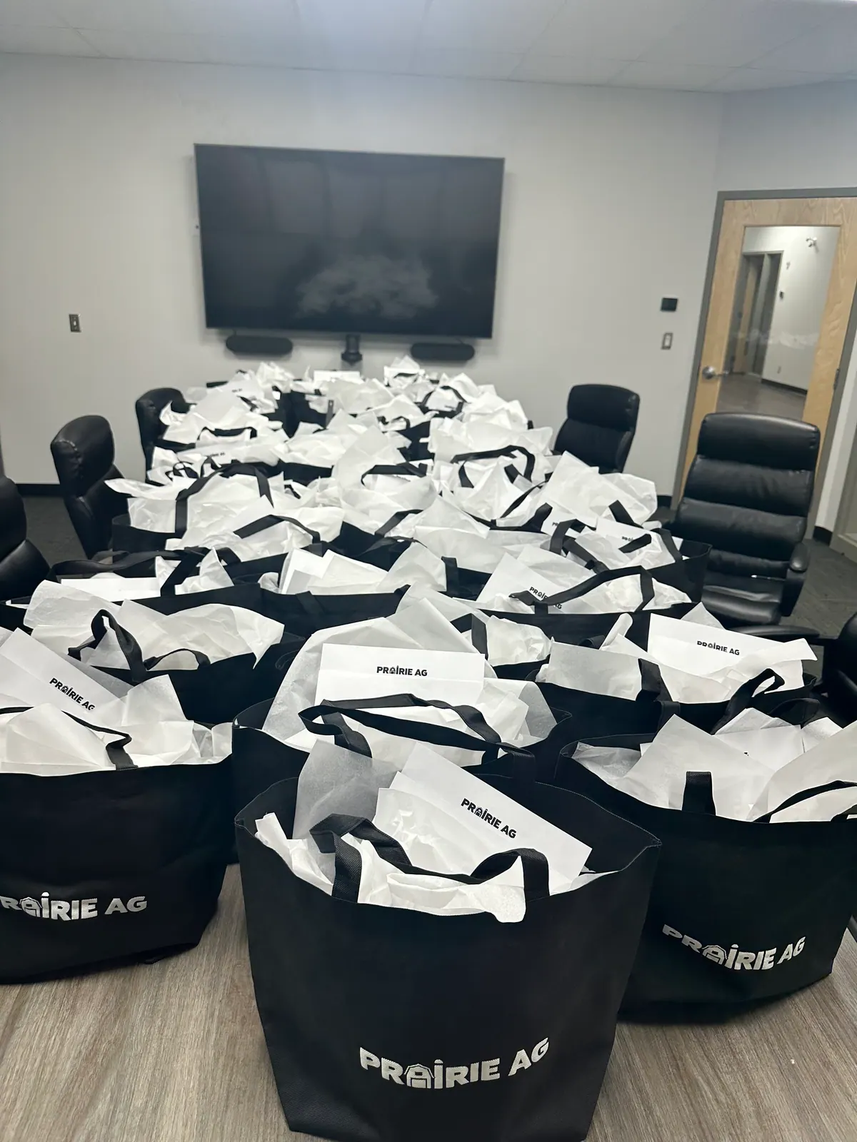 Boardroom table covered in Prairie Ag branded tote bags ready for customers
