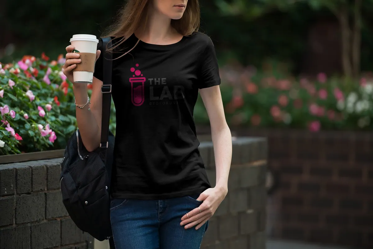 Woman with a takeaway coffee wearing a black The Lab T-shirt