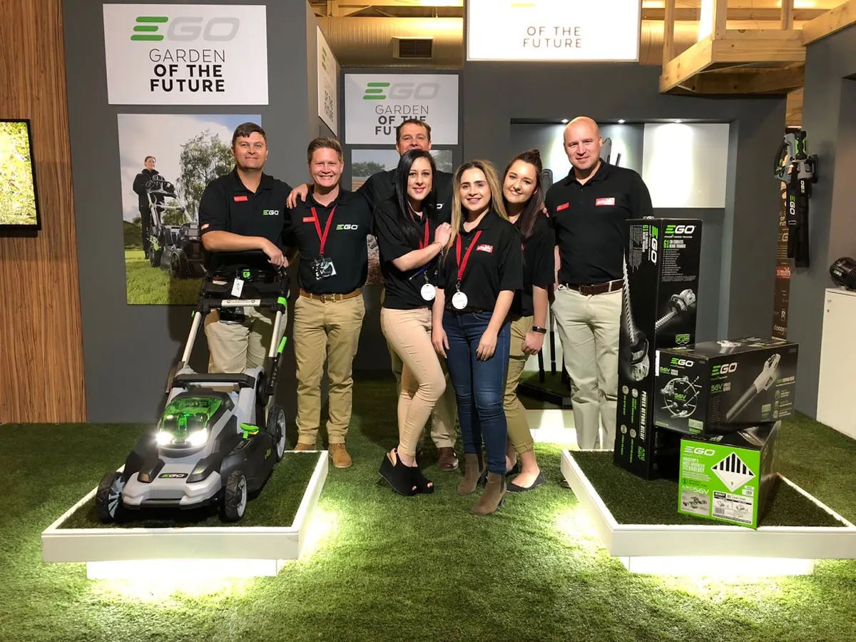 EGO stand staff in branded shirts beside a battery mower