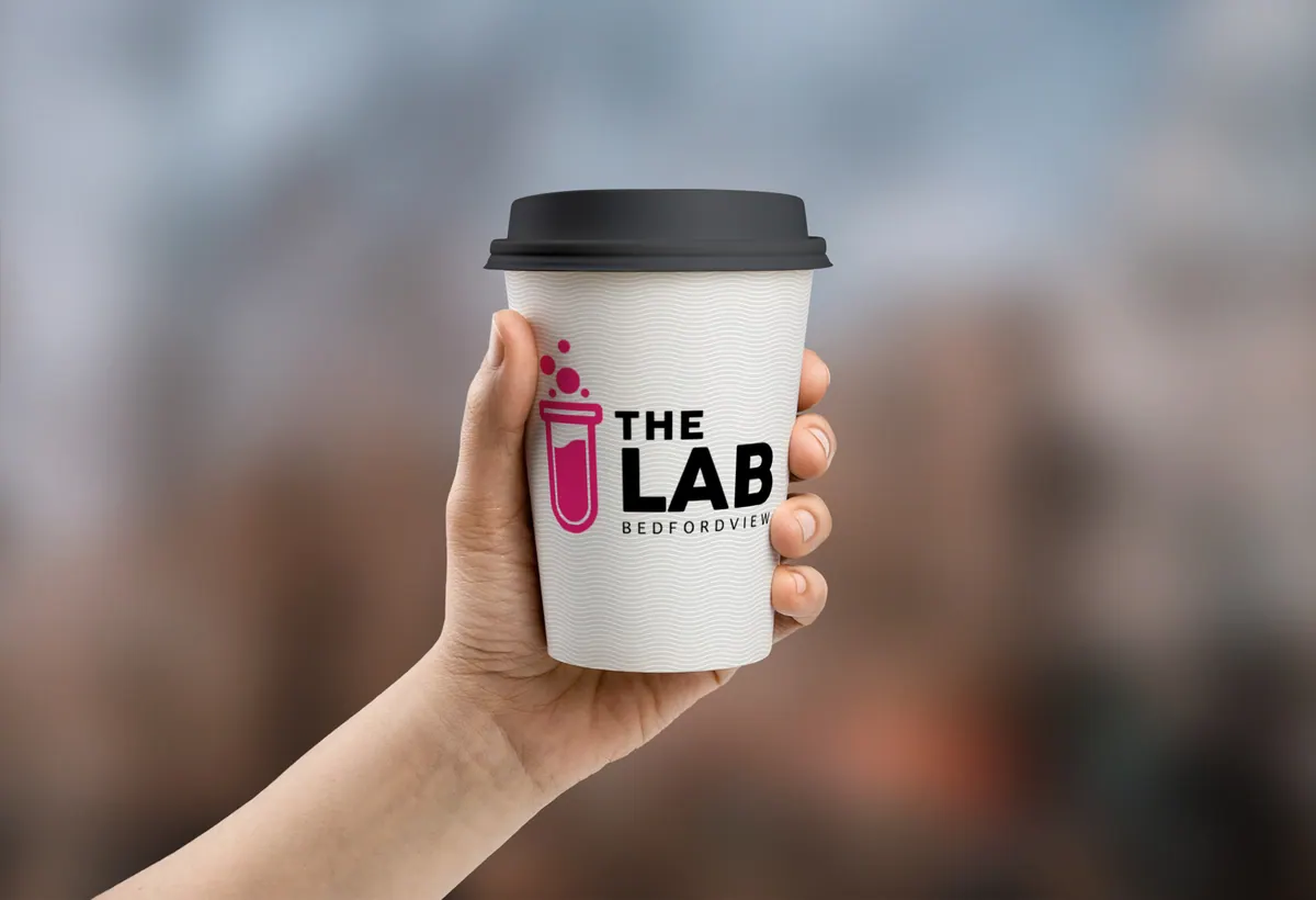 Hand holding a The Lab takeaway coffee cup