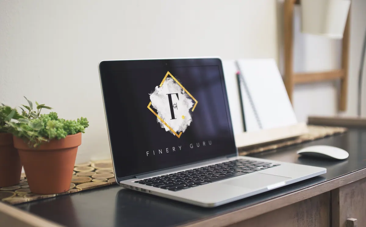 Laptop on a desk displaying the Finery Guru logo