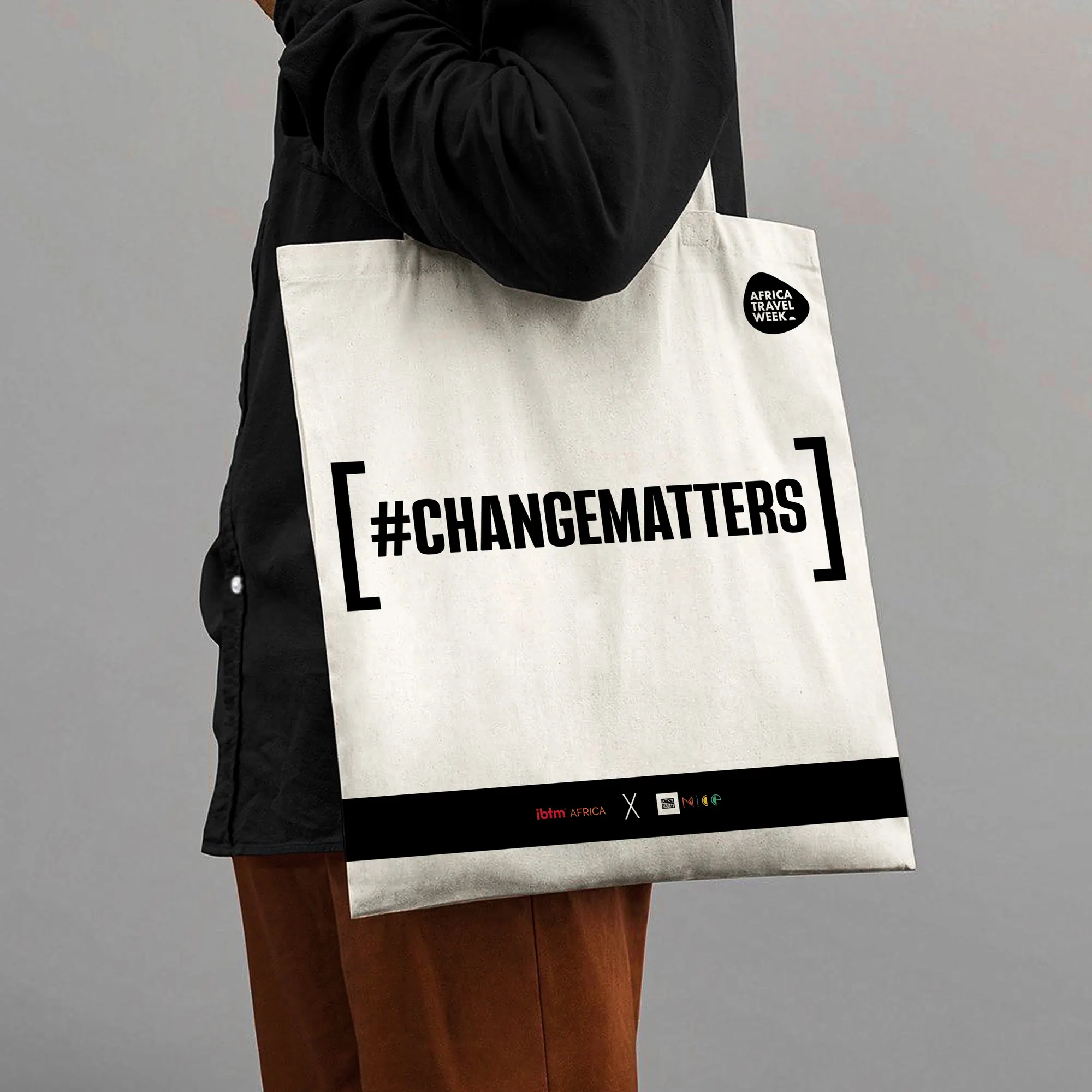 Person carrying a white canvas tote printed with #CHANGEMATTERS