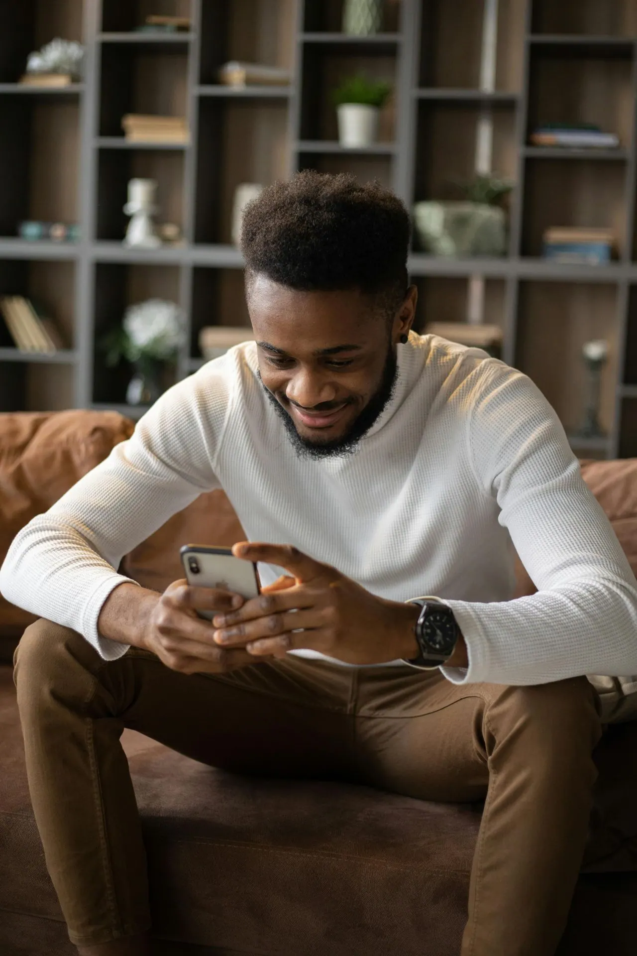 Man smiling at his phone while using the Argo app on a couch