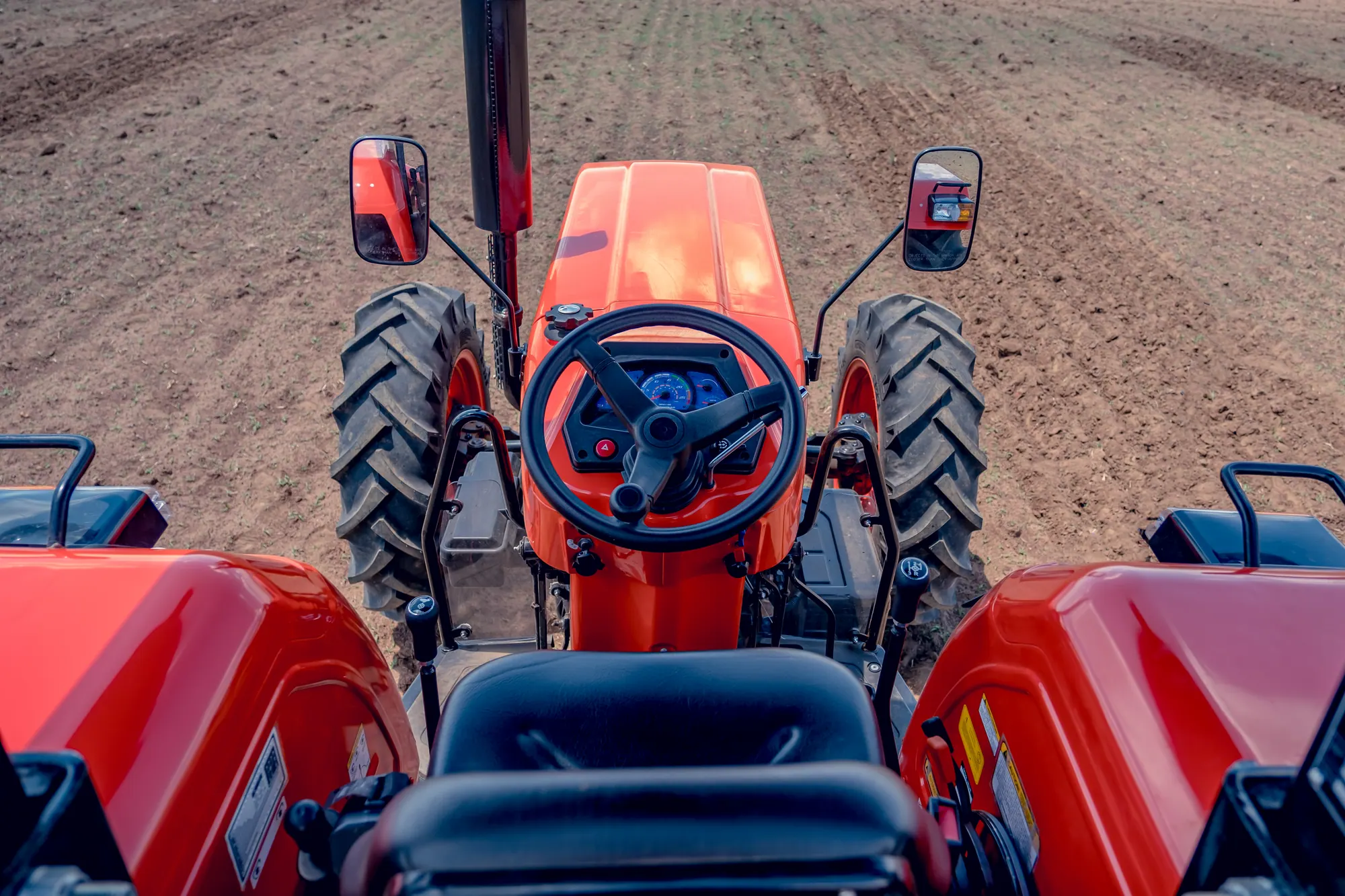 Low-angle view of an orange E-Kubota tractor bonnet and cab in a field