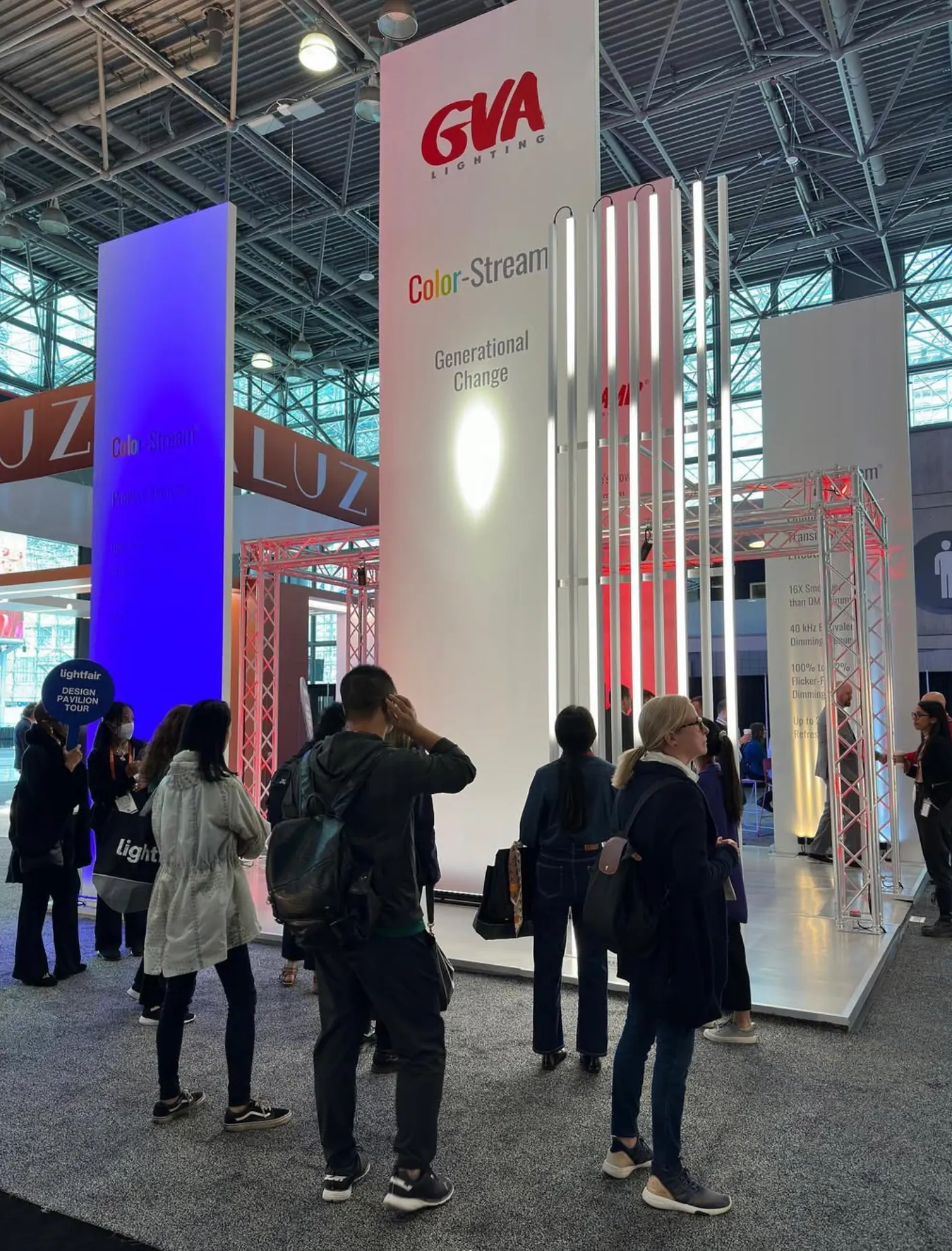 Visitors at the GVA Lighting stand at Lightfair New York, with tall branded towers and coloured light