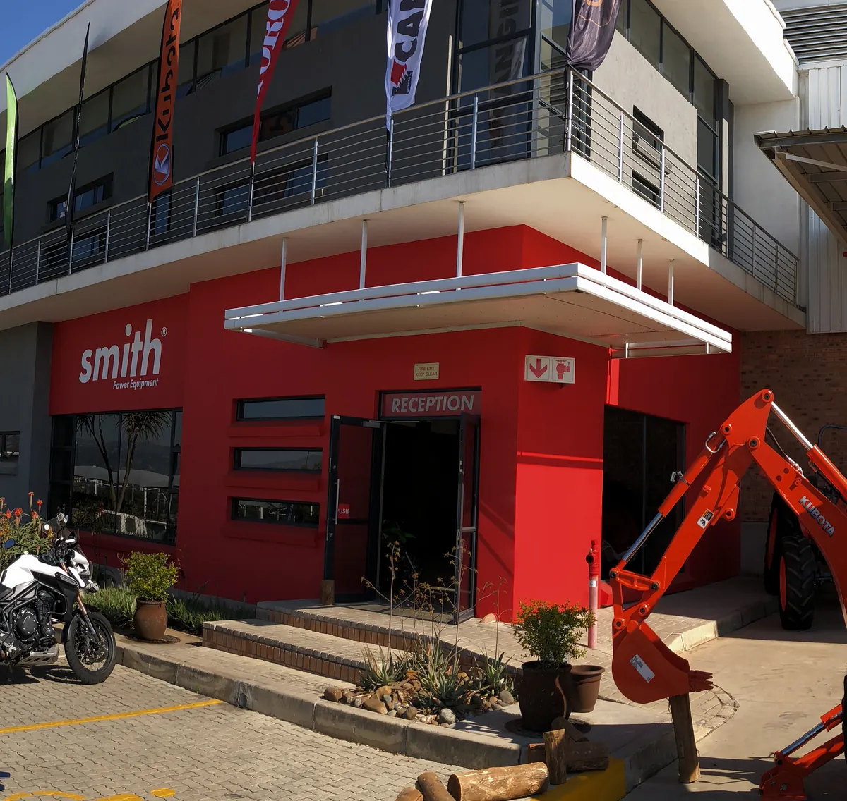 The red Smith Power Equipment facade and sign at the head office, a Kubota backhoe out front